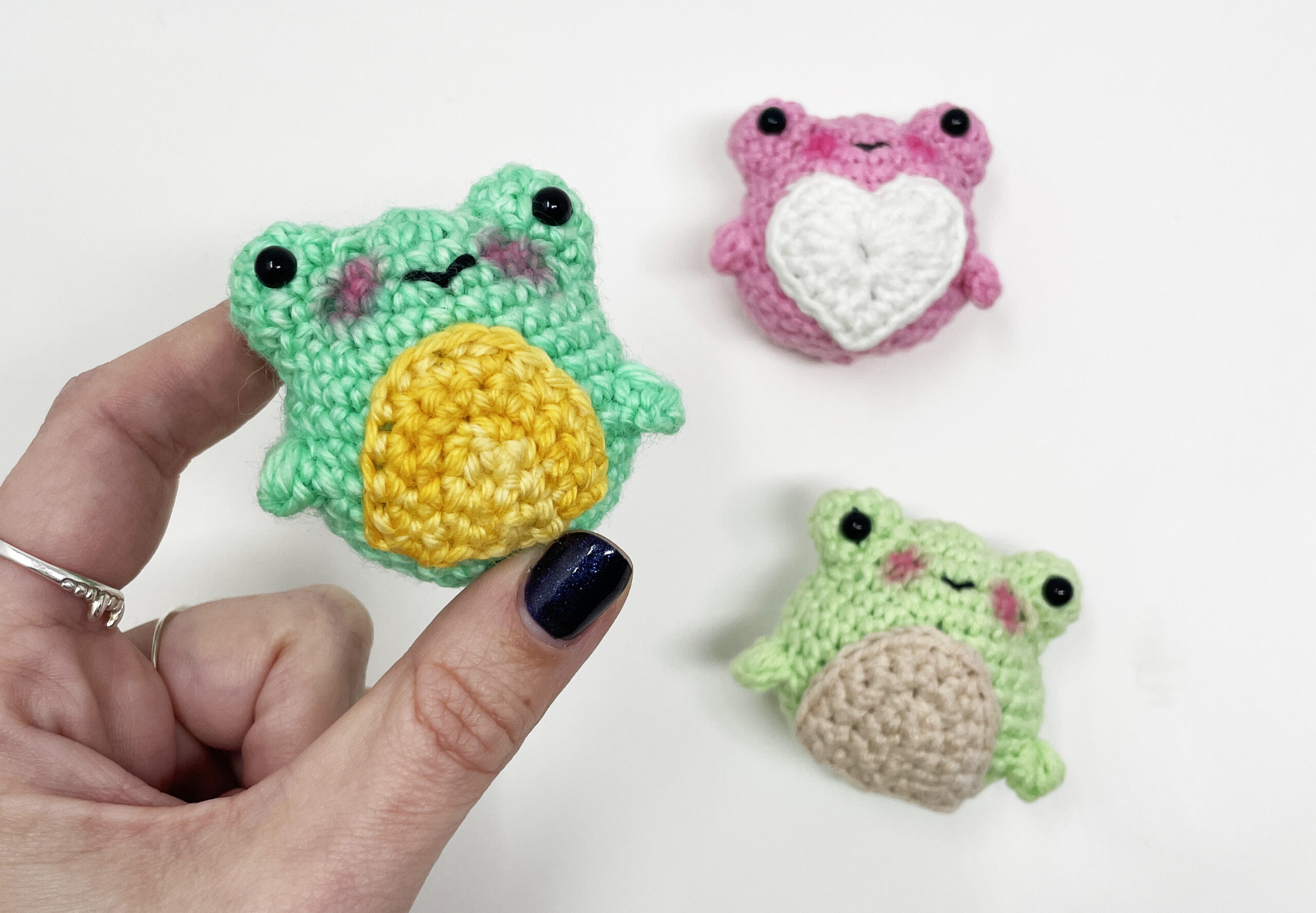 small crochet kawaii style frogs in various colors